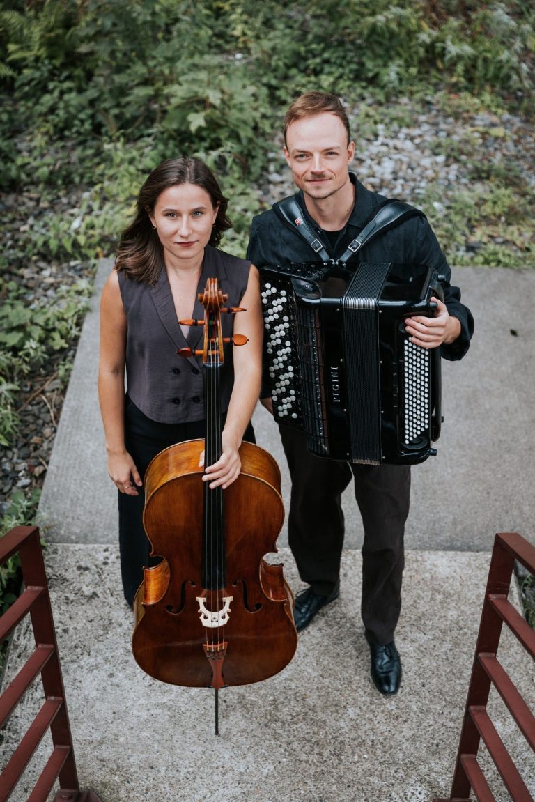 Duo Klangtreff Zwei Musiker, einer mit Akkordeon und die andere mit Cello, stehen vor einer Backsteinmauer.